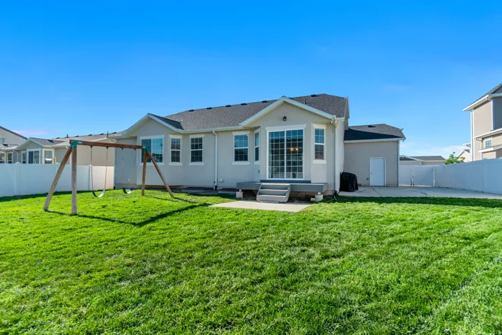 Expansive rear yard featuring a manicured lawn, full privacy fencing, and a built-in patio