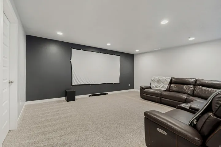 Recessed ceiling lighting with a dark accent wall and light-colored carpeting