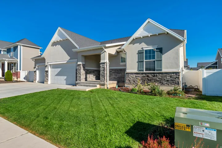 Stucco exterior with stone veneer accents, covered entry, attached two-car garage, and a concrete driveway