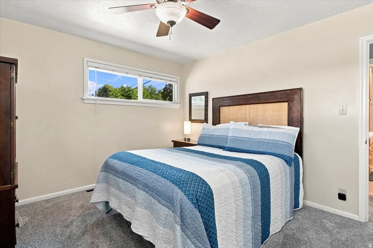 Carpeted bedroom with a ceiling fan, horizontal window, and neutral wall tones