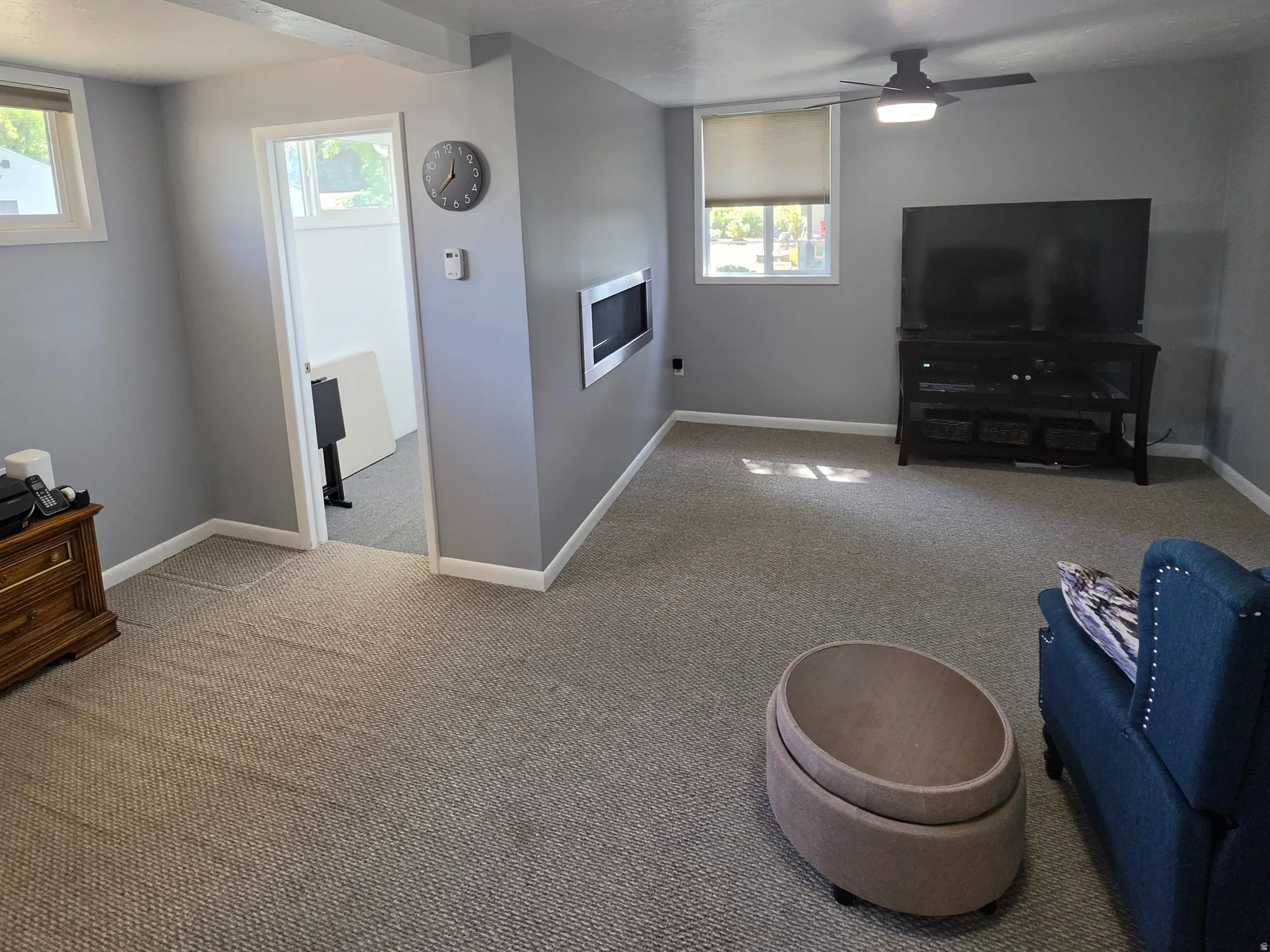 Recessed lighting, wall-mounted electric fireplace, carpeted flooring, and two ceiling fans with integrated lighting