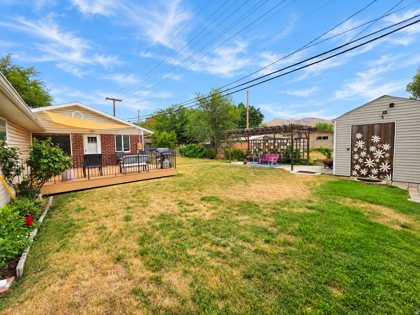 Spacious backyard oasis featuring a manicured lawn, mature landscaping, and a detached storage shed