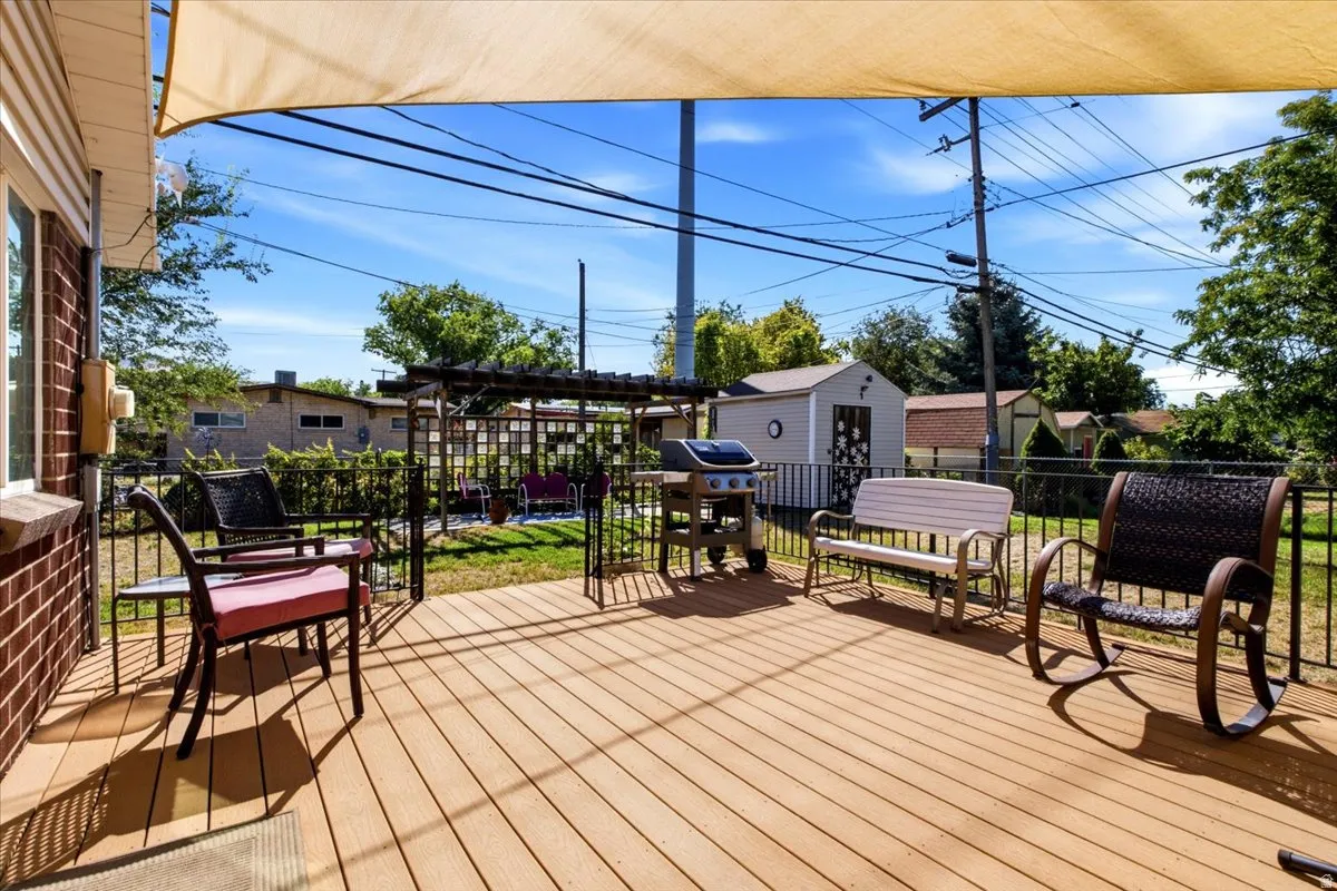 Expansive outdoor deck with composite decking, partial overhead shade structure, and direct access to a fenced yard