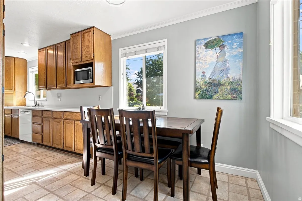 Kitchen featuring wood cabinetry, a stainless steel microwave, white countertops, and a white dishwasher