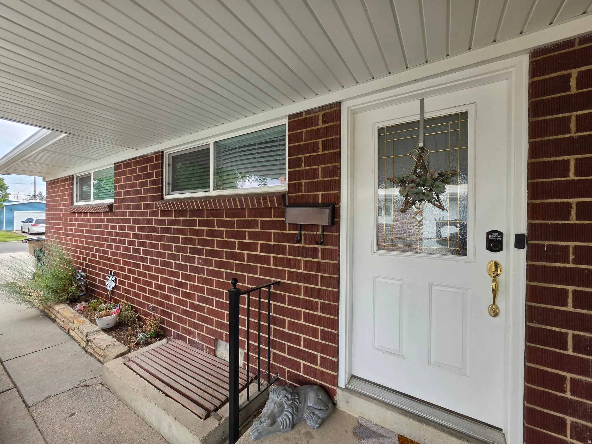 Welcoming front entrance featuring a white six-panel entry door with brass hardware and decorative wreath, flanked by red brick exterior walls