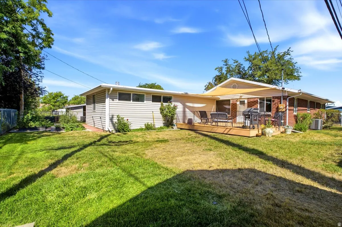 Expansive yard with wood deck, brick siding, vinyl siding, and a chain link fence