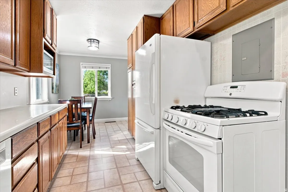 Galley kitchen featuring wood cabinetry, white countertops, built-in microwave, and tile flooring
