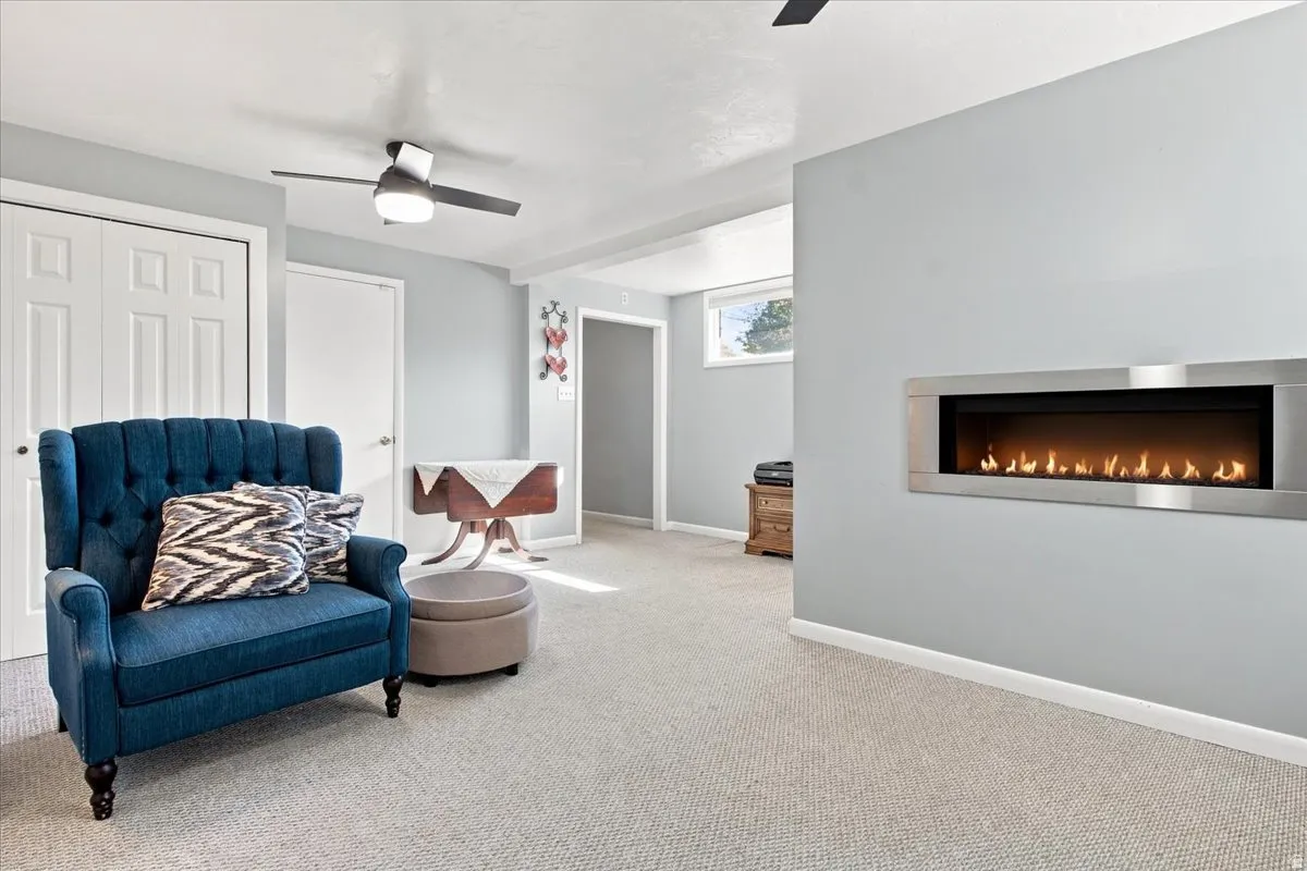 Recessed electric fireplace with a stainless steel frame, wall-to-wall carpeting, and a ceiling fan with integrated lighting