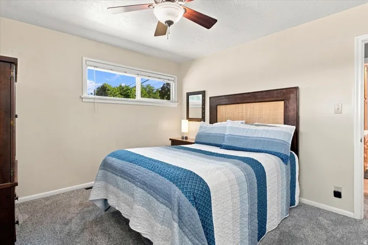 Carpeted bedroom with a ceiling fan, horizontal window, and neutral wall tones