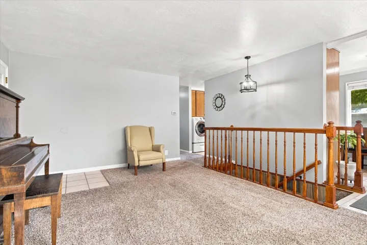 Neutral-toned carpeting, light gray wall finishes, and a wood railing with turned balusters