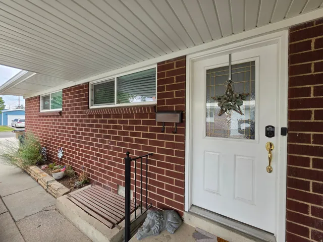 Welcoming front entrance featuring a white six-panel entry door with brass hardware and decorative wreath, flanked by red brick exterior walls