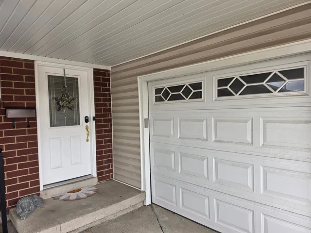 Welcoming front entry featuring a white six-panel door with decorative hardware, complemented by a brick facade and covered concrete stoop