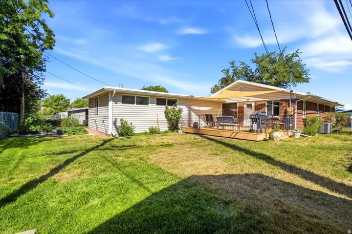 Expansive yard with wood deck, brick siding, vinyl siding, and a chain link fence