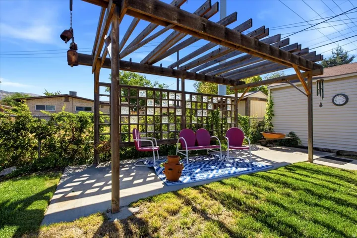 Expansive outdoor space featuring a wood pergola, concrete patio, grass lawn, privacy lattice with glass blocks, and a detached shed
