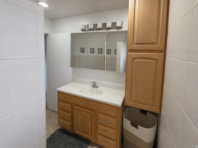 Vanity with integrated sink, light wood cabinetry, and a white countertop