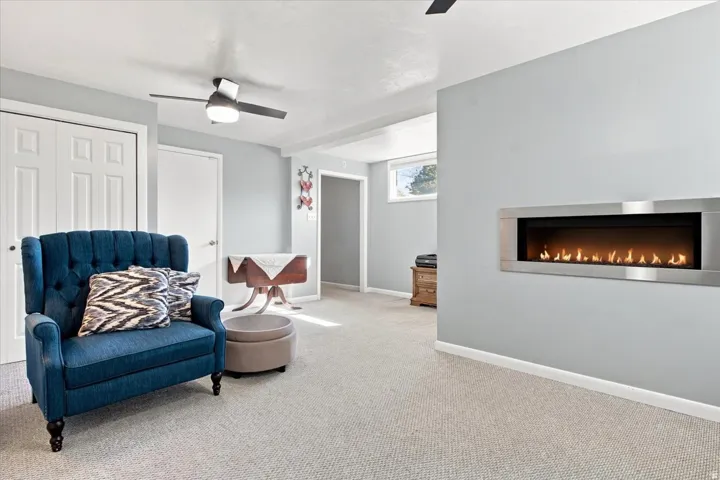 Recessed electric fireplace with a stainless steel frame, wall-to-wall carpeting, and a ceiling fan with integrated lighting