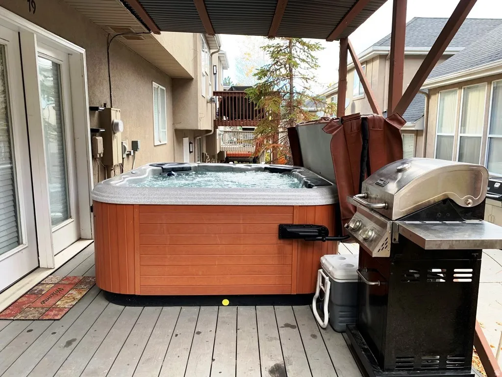 Deck with a built-in spa, dual glass-paneled doors, wood-finish siding, and a corrugated metal patio cover