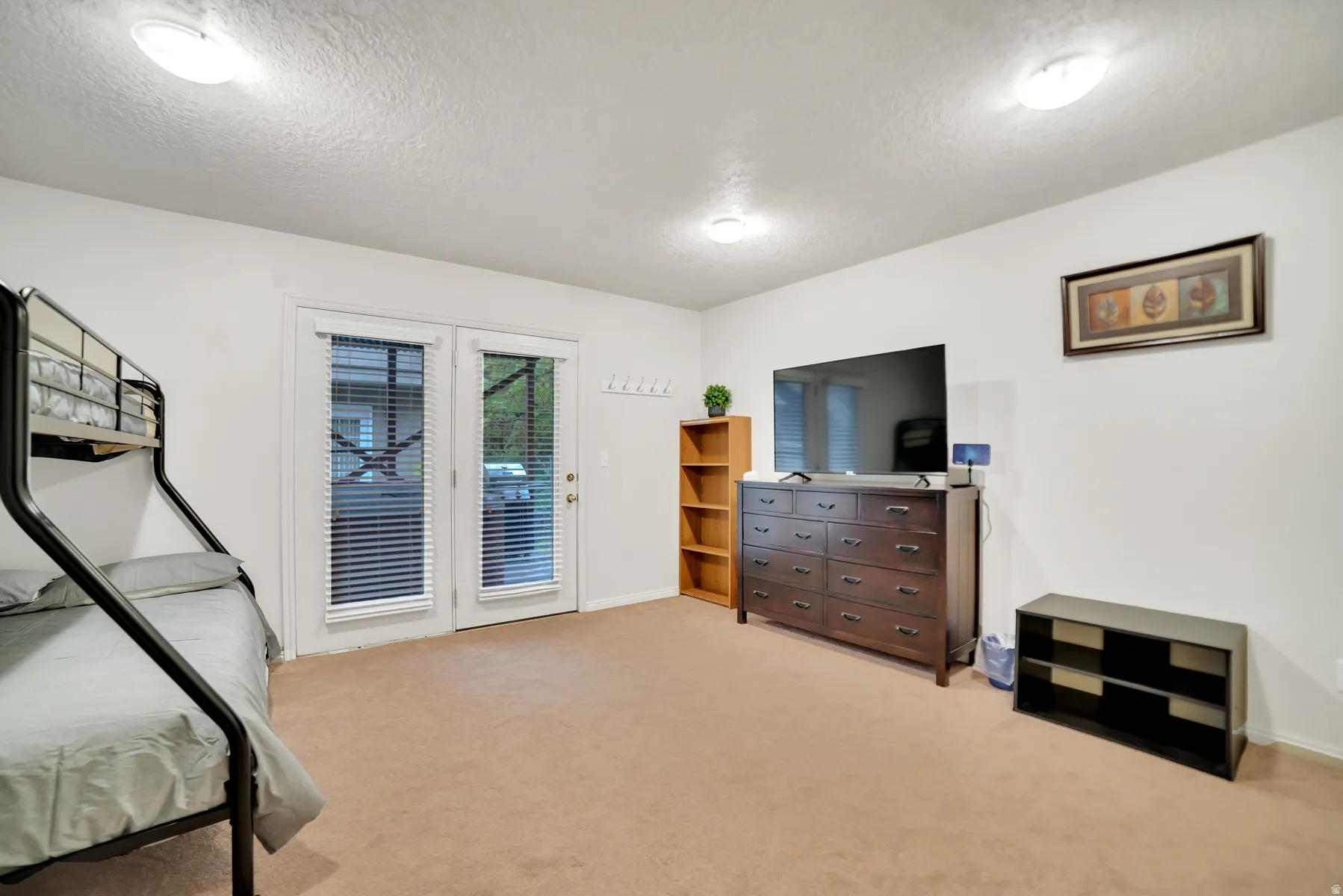 White walls with a textured ceiling, two flush-mount ceiling lights, and light-toned carpeting