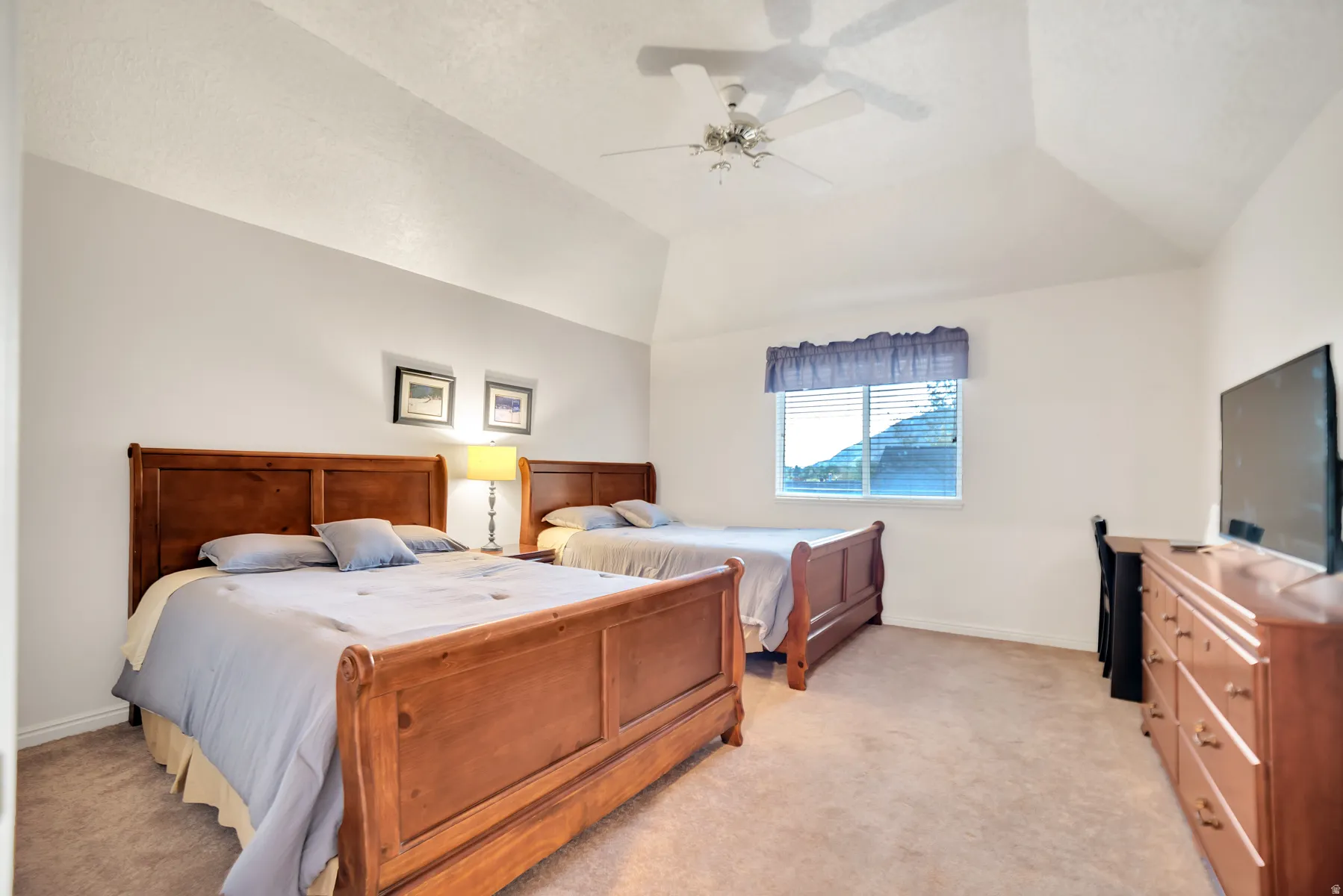 Carpeted flooring, vaulted ceiling, ceiling fan, and window with blinds