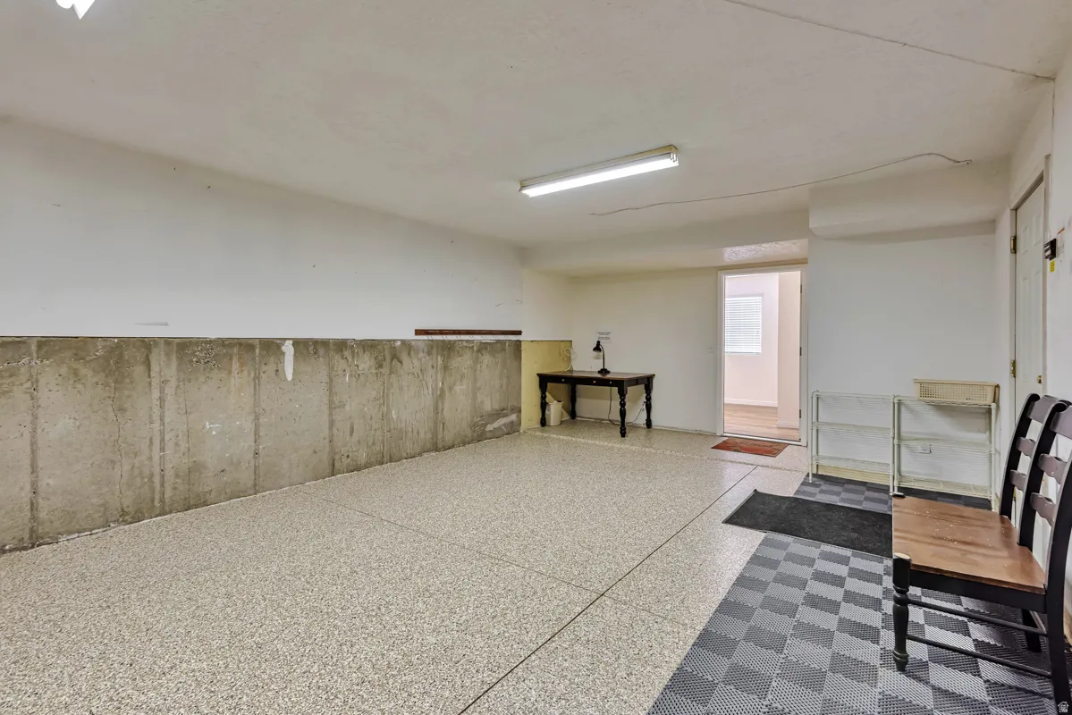 Epoxy-coated concrete flooring, concrete half-wall, white painted walls, and overhead fluorescent lighting