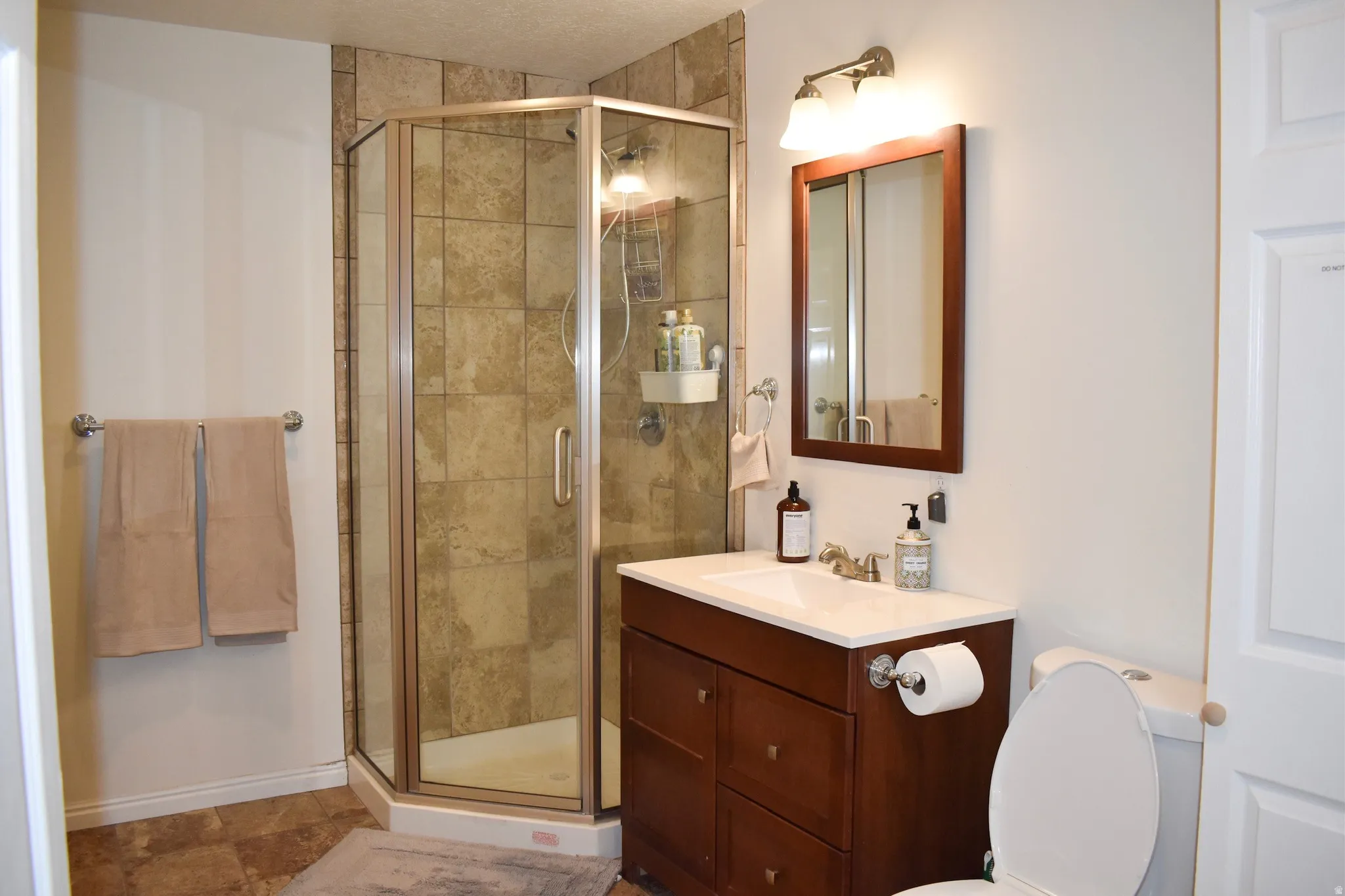 Corner glass-enclosed shower with tiled surround