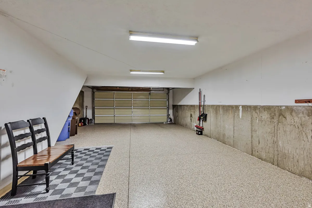 Attached garage with a roll-up door, fluorescent lighting, and speckled epoxy flooring