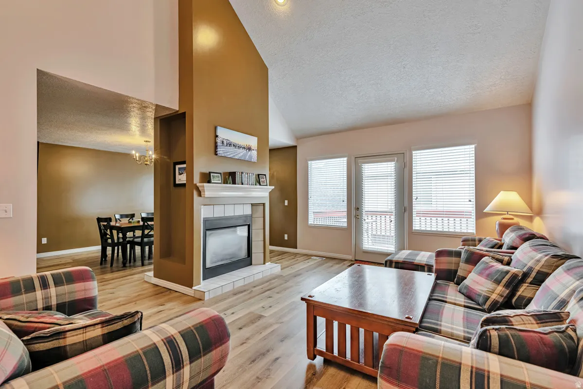 Vaulted ceilings, a tile fireplace, and wood-finish flooring define this living space, featuring a glass-paneled door