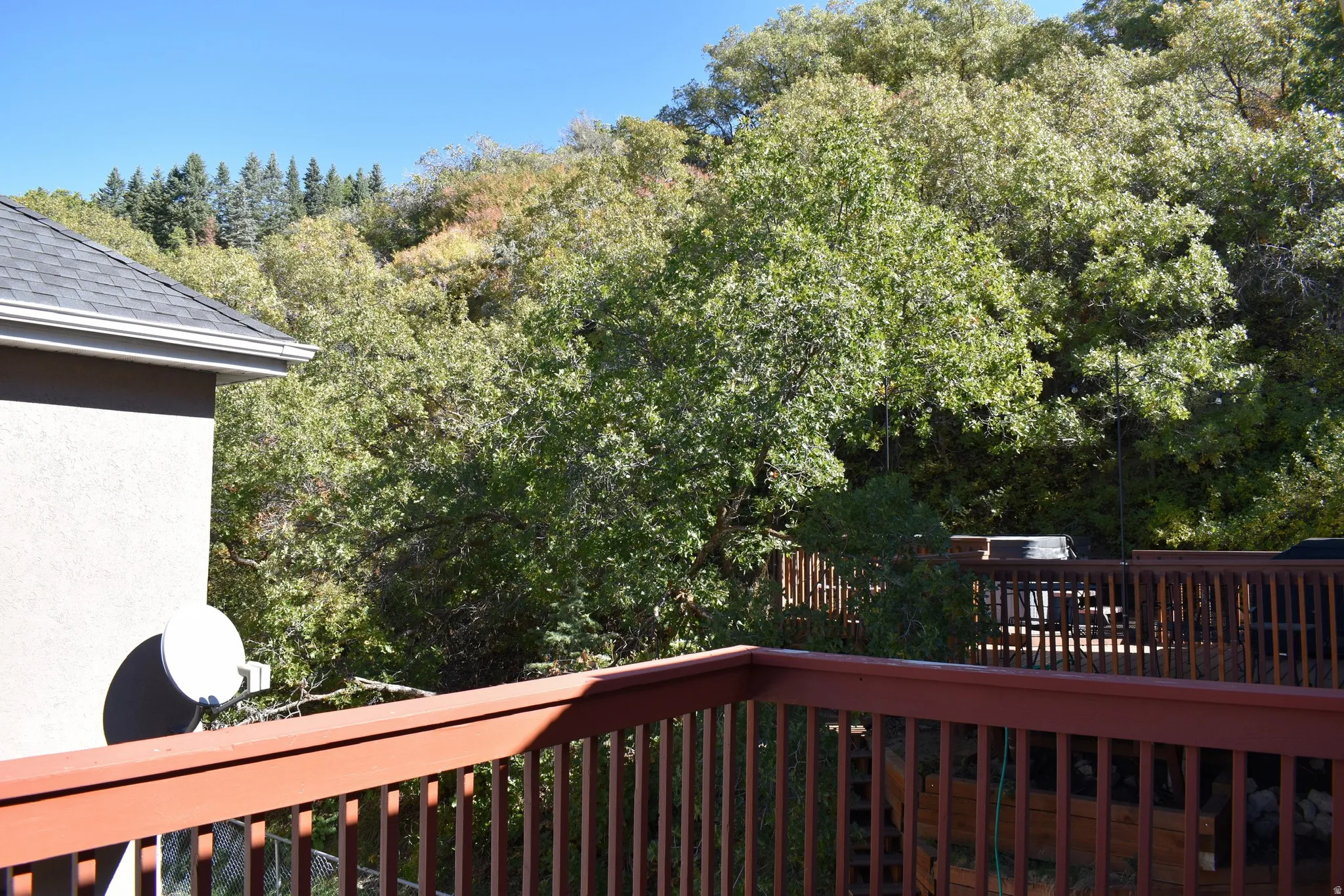 Multi-level wood deck with a natural wood-tone finish, featuring vertical balusters and a prominent railing