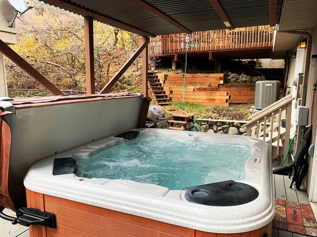 Covered outdoor spa with privacy wall, featuring a corrugated metal roof and wood support beams