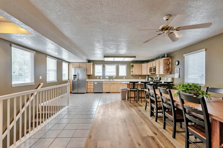 Open-concept living space featuring wood-finish flooring, a kitchen with stainless steel appliances, and a dining area with a ceiling fan