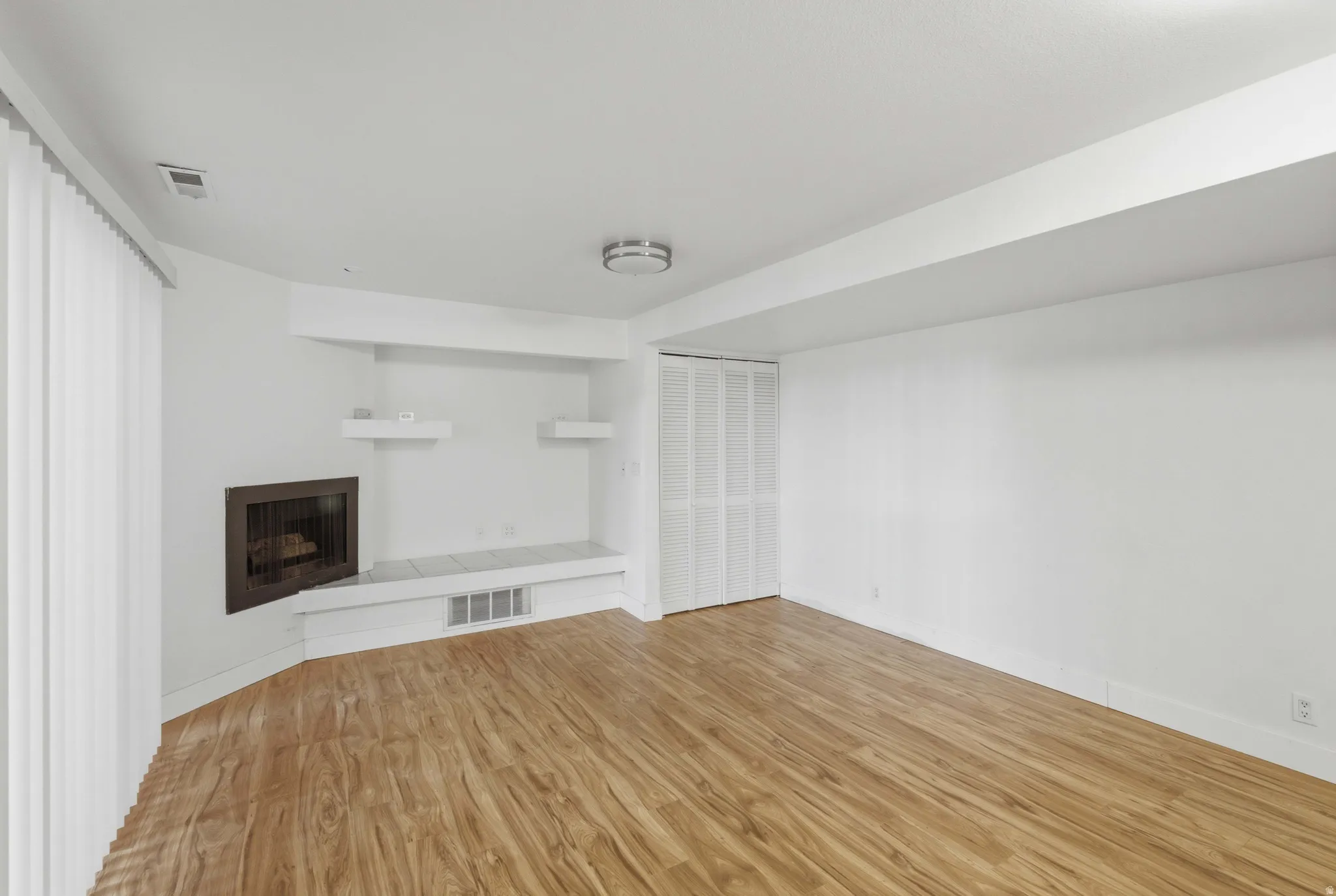 Wood-finish flooring, built-in fireplace, integrated shelving, and a bi-fold closet