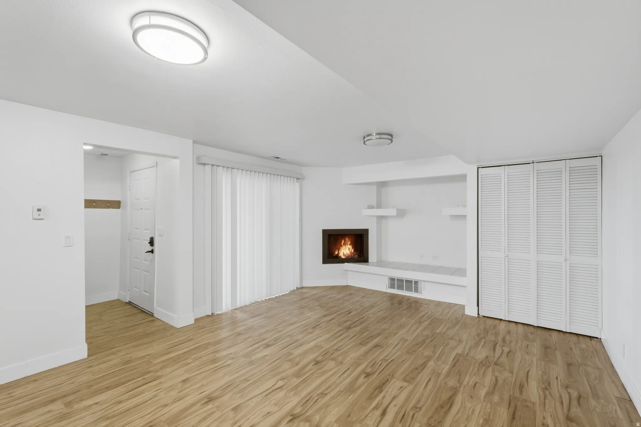 Wood-finish flooring throughout, featuring a corner fireplace with a white mantel and hearth