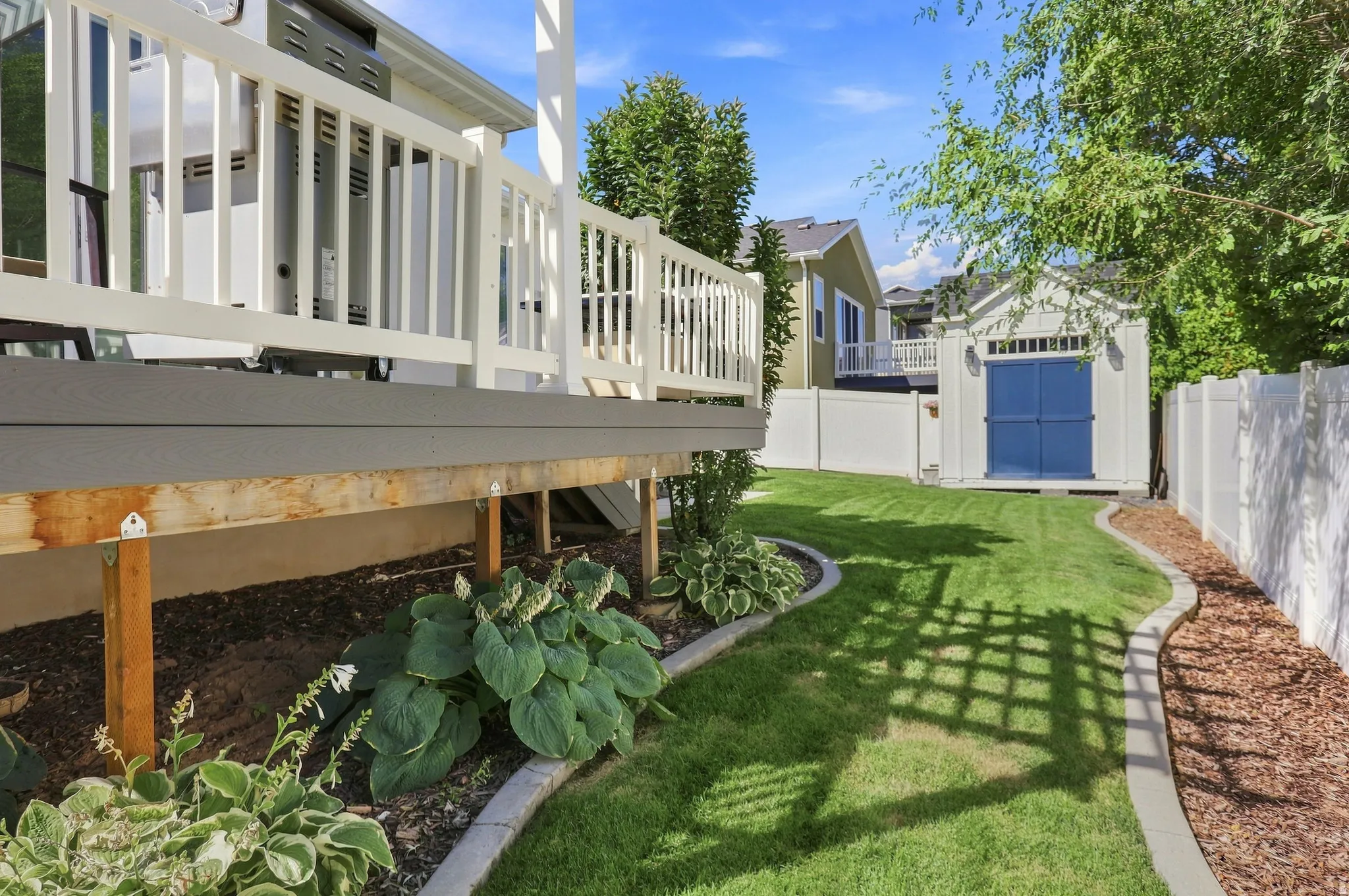 Expansive lawn with concrete curbing, mature landscaping, and a fenced perimeter