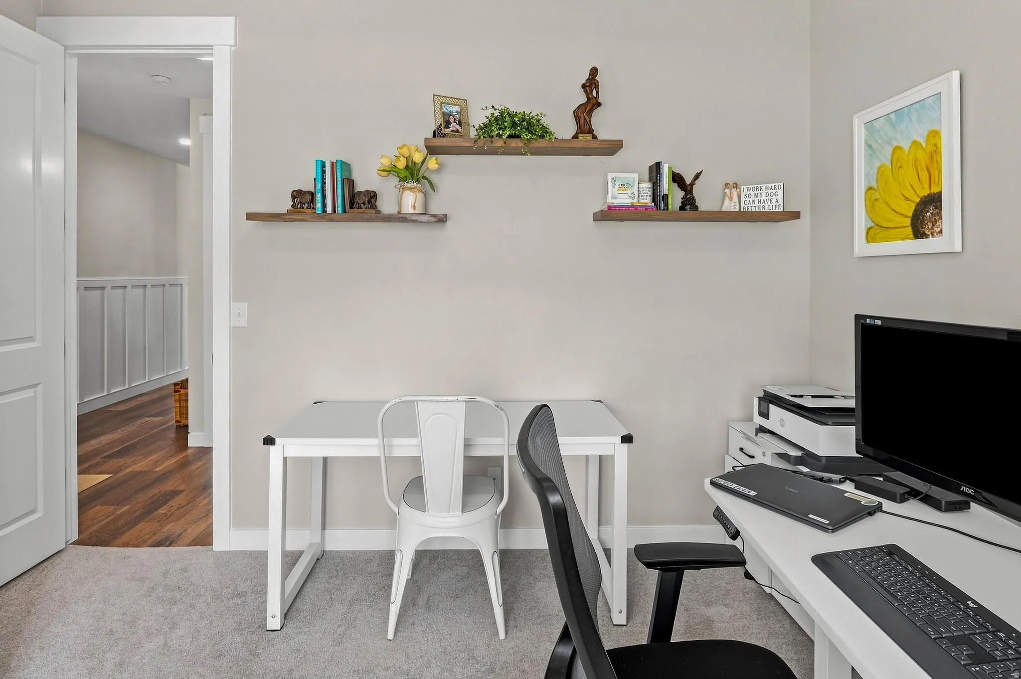 Light-toned wall paint, two wood-finish floating shelves, light gray carpeting, and a white interior door frame