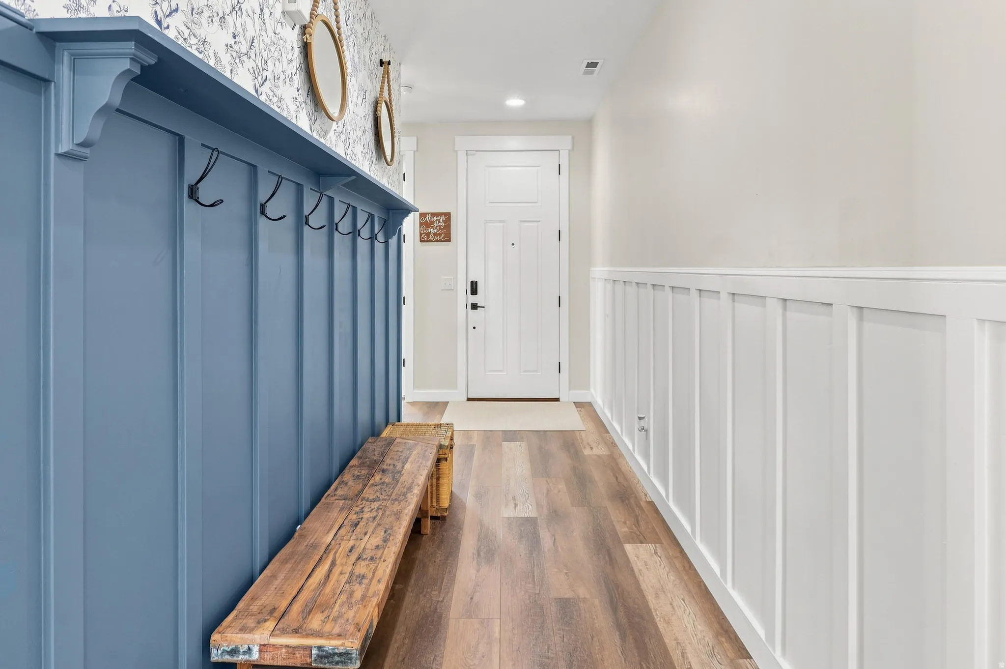 Board and batten wall paneling, wood-finish flooring, built-in coat hooks, and a paneled entry door