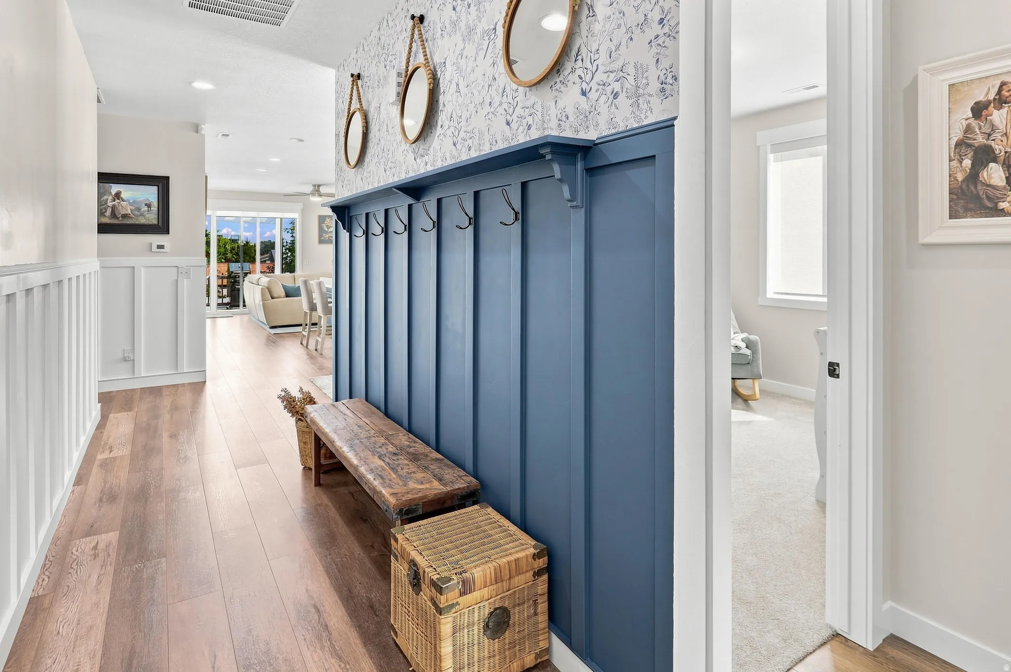 Wood-finish flooring throughout, board and batten wall paneling, built-in coat rack, recessed lighting, and a white interior door