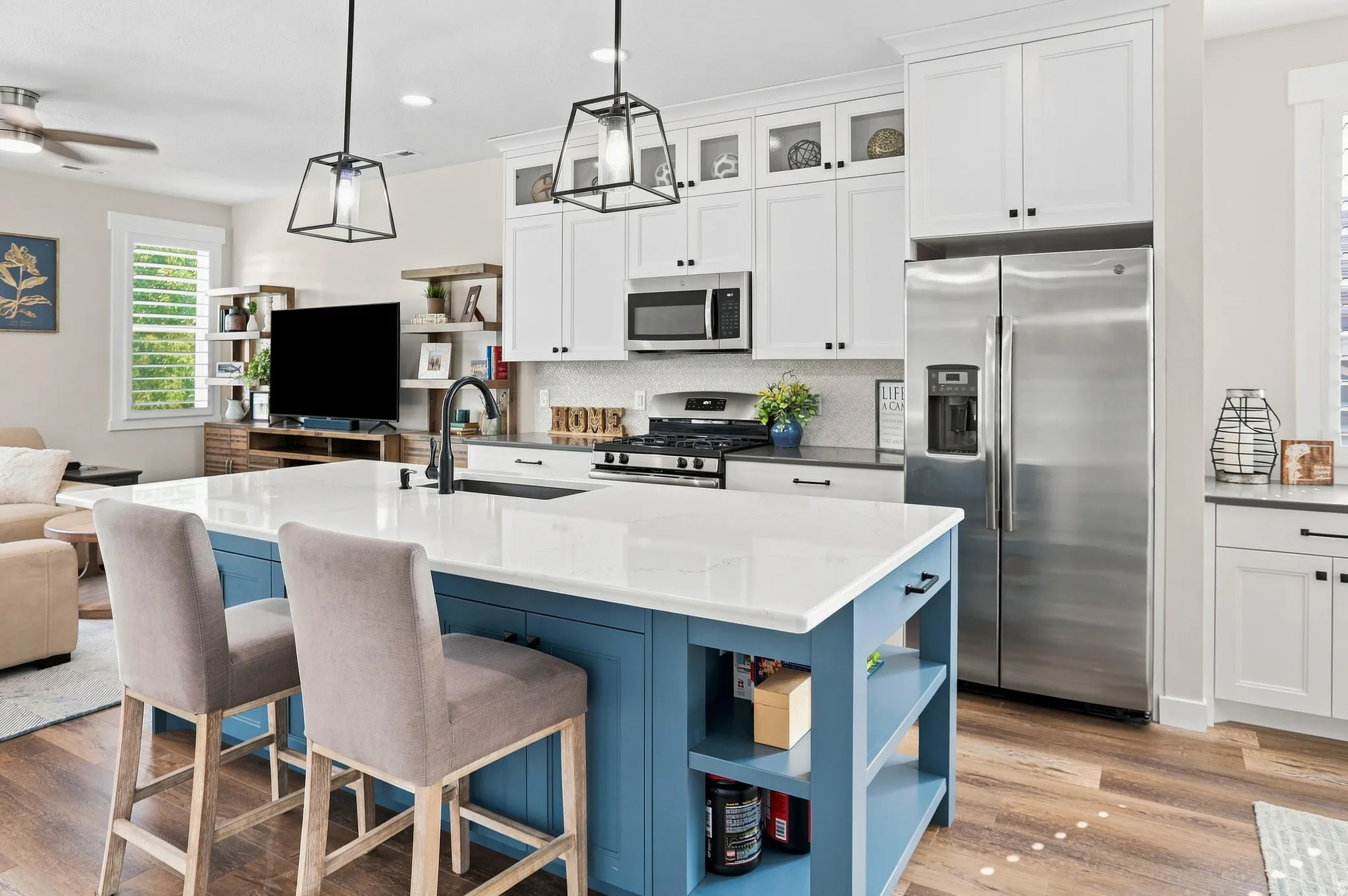 Kitchen featuring a blue island with a white countertop, stainless steel appliances, white cabinetry, and wood-finish flooring