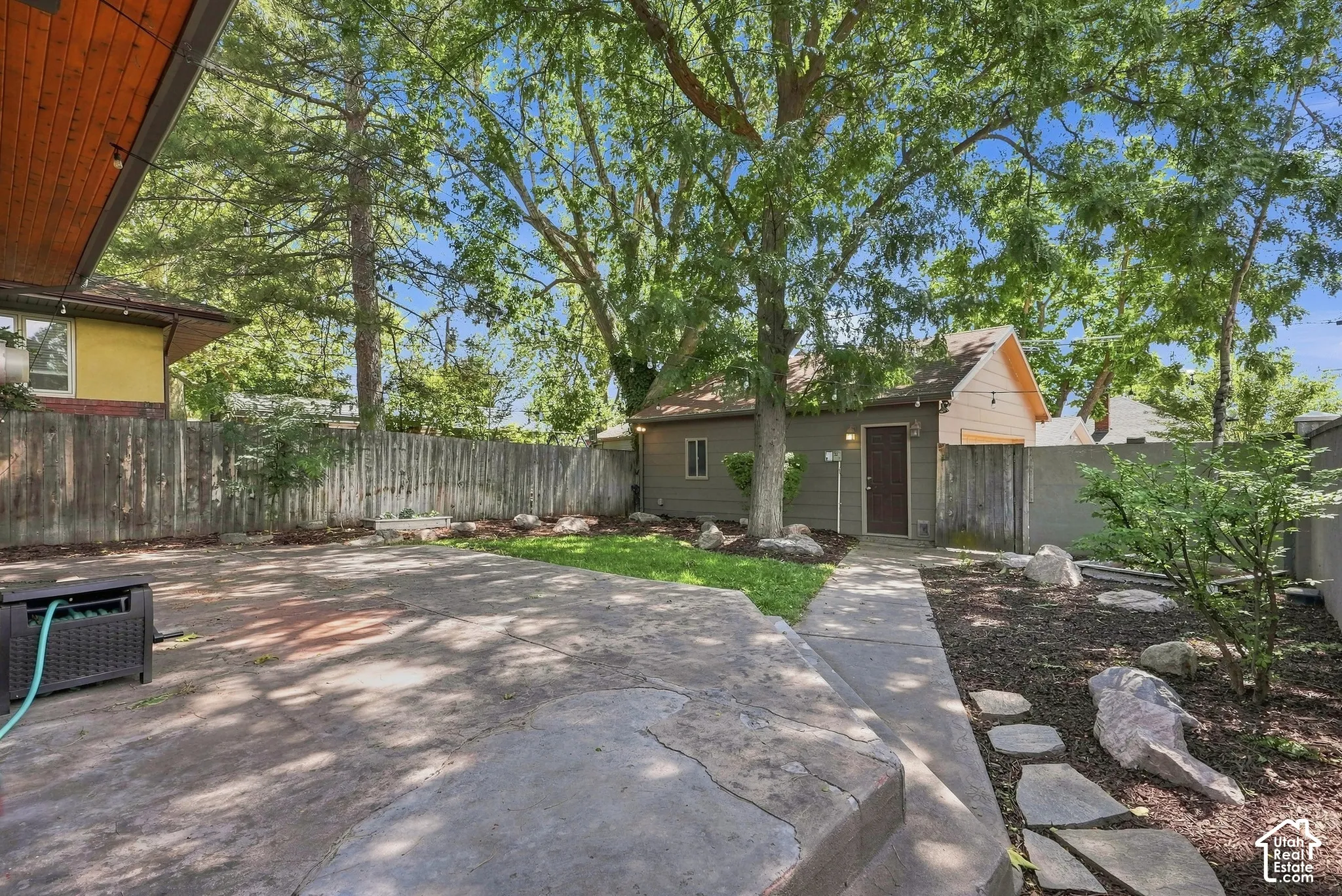 Mature shade trees and expansive hardscaped patio create an inviting outdoor retreat