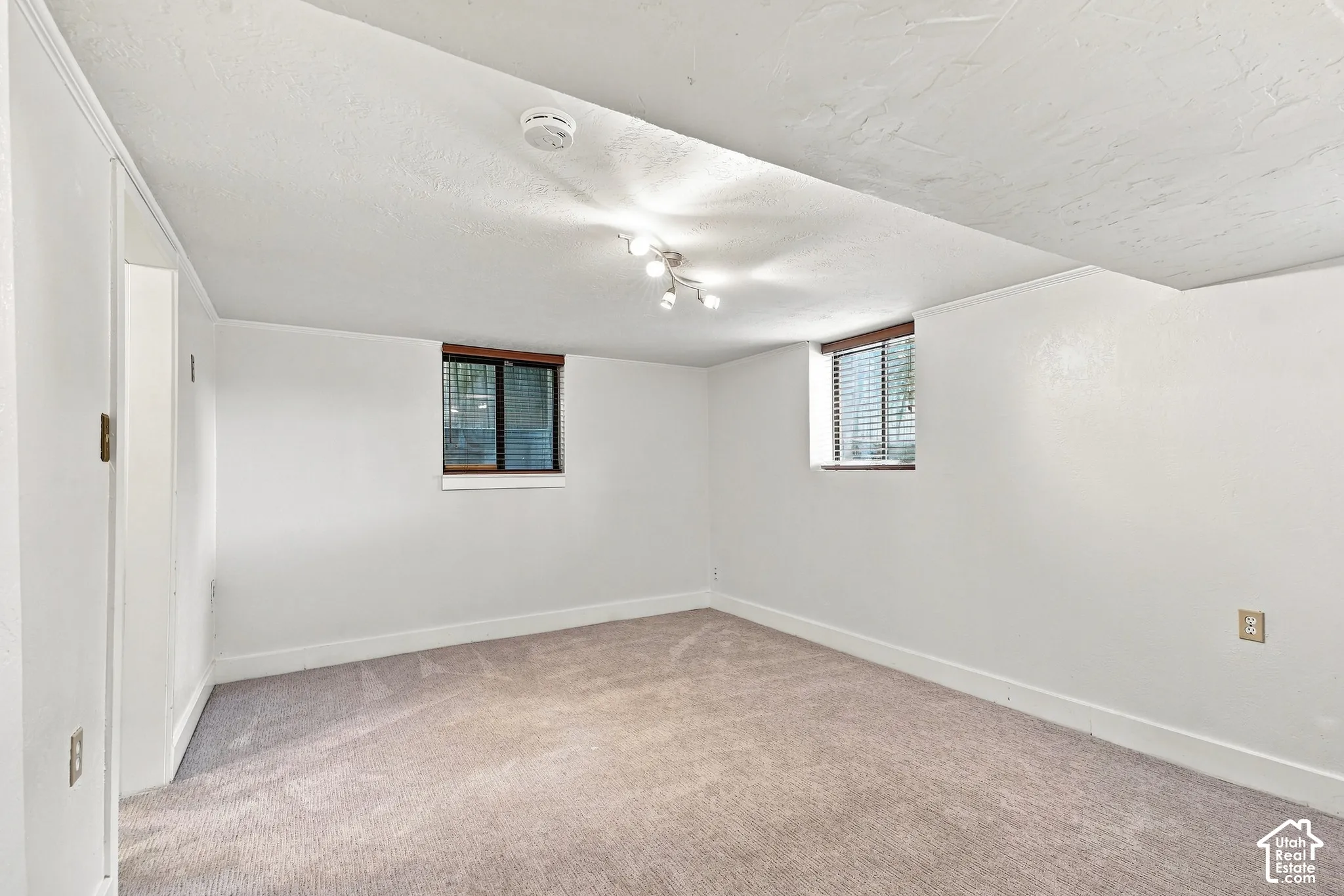 Recessed window with wood-finish trim, wall-mounted track lighting, and light-toned carpeting