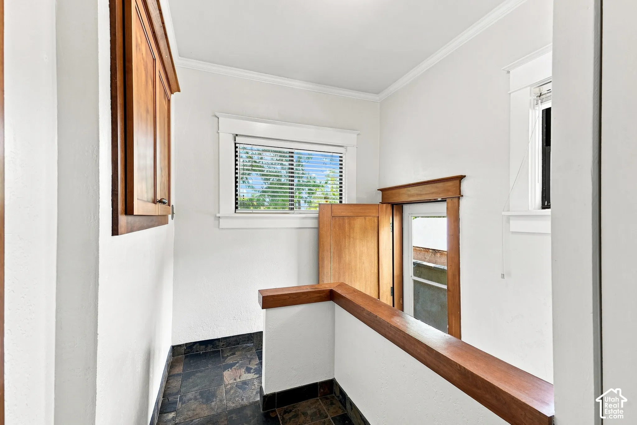 Built-in wood cabinetry, natural wood trim, white walls, and dark tile flooring