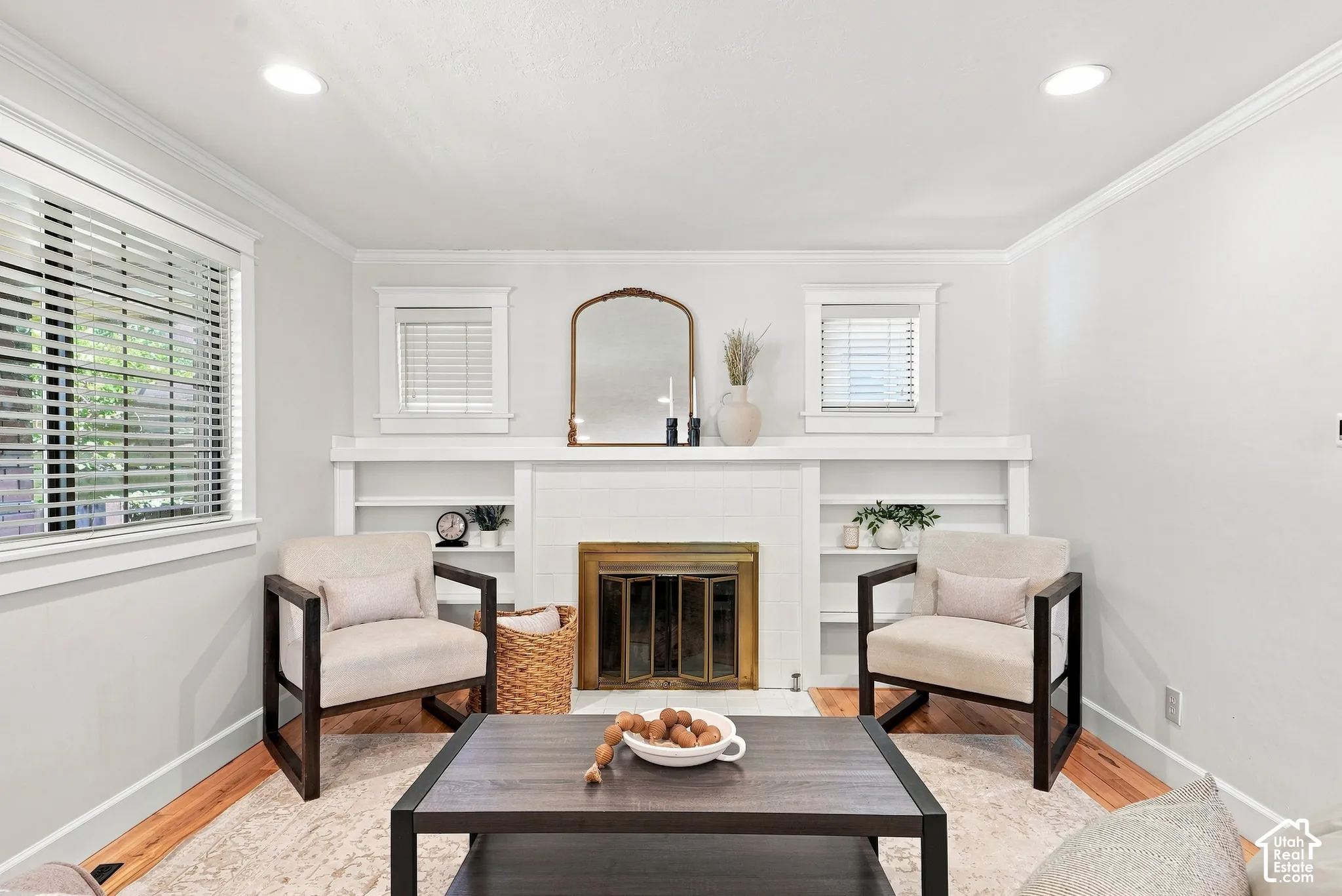 Recessed ceiling lighting, wood-finish flooring, white crown molding, and a fireplace with integrated shelving