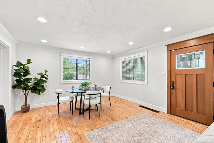 Hardwood flooring, recessed lighting, craftsman-style entry door with leaded glass, white trim, and multiple windows
