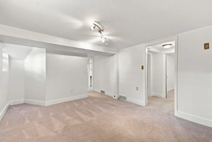 Spacious open floor plan with neutral carpeting, white walls, and recessed ceiling lighting