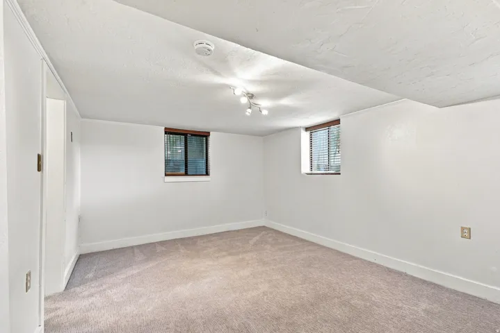 Recessed window with wood-finish trim, wall-mounted track lighting, and light-toned carpeting