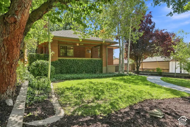 Charming mid-century home set on a lush, manicured lawn shaded by mature trees