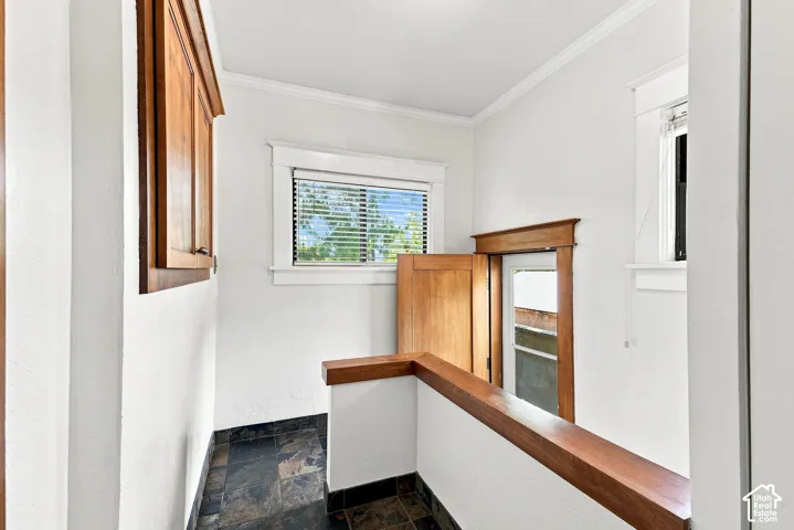 Built-in wood cabinetry, natural wood trim, white walls, and dark tile flooring