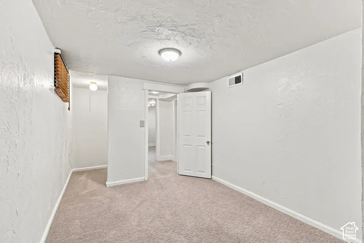 Finished basement featuring neutral carpet flooring, white drywall, recessed ceiling lighting, and white interior doors