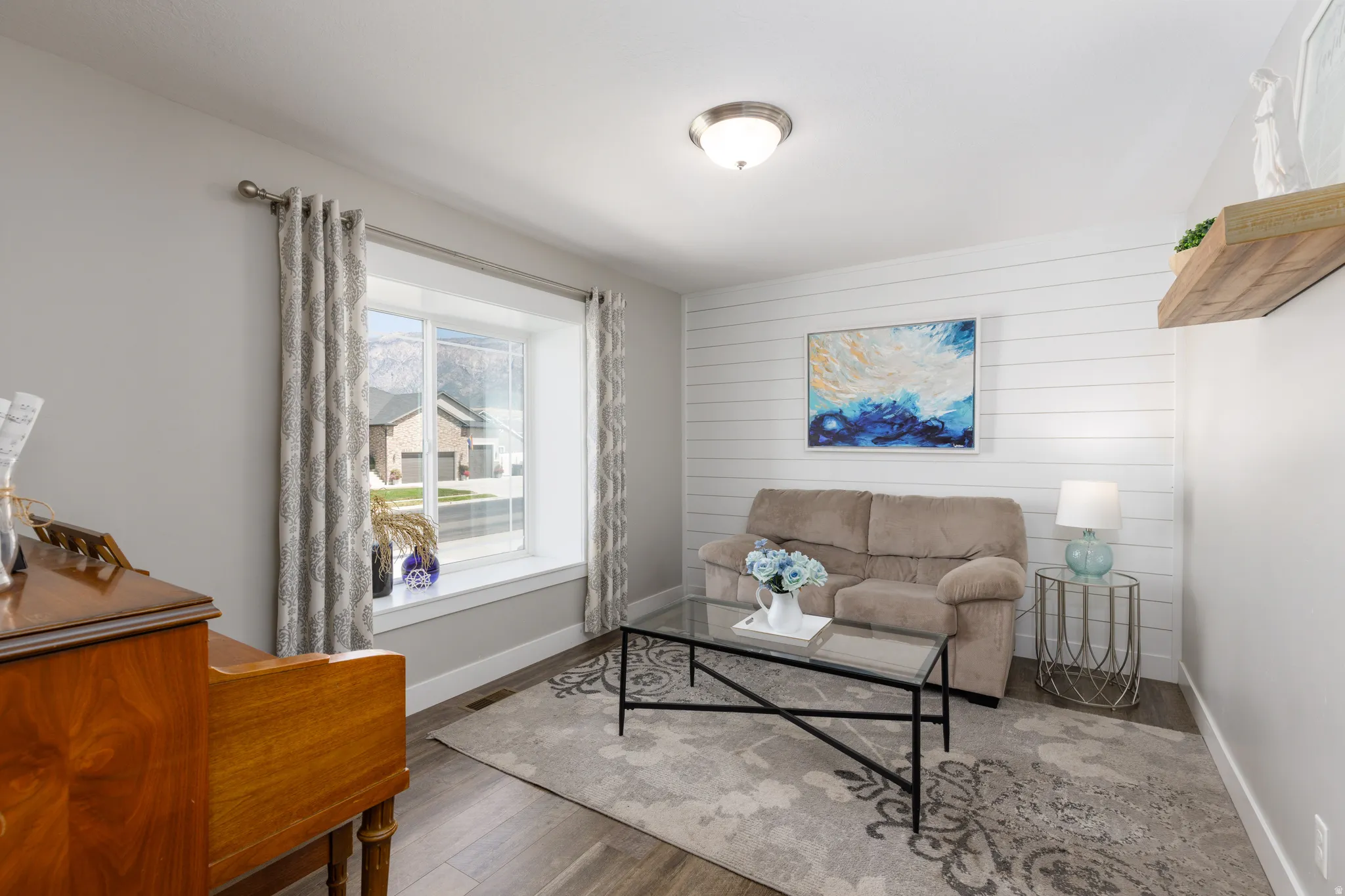 Wood-finish flooring, white shiplap accent wall, recessed lighting, and a large window with white trim