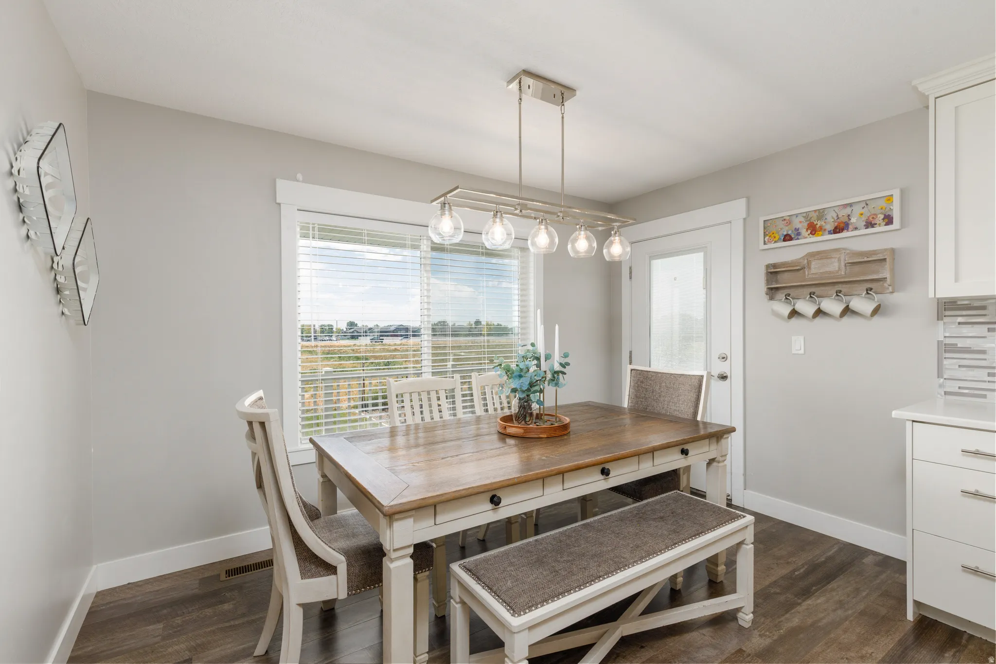 Wood-finish flooring, white trim, shaker-style cabinetry, and a glass-paneled door