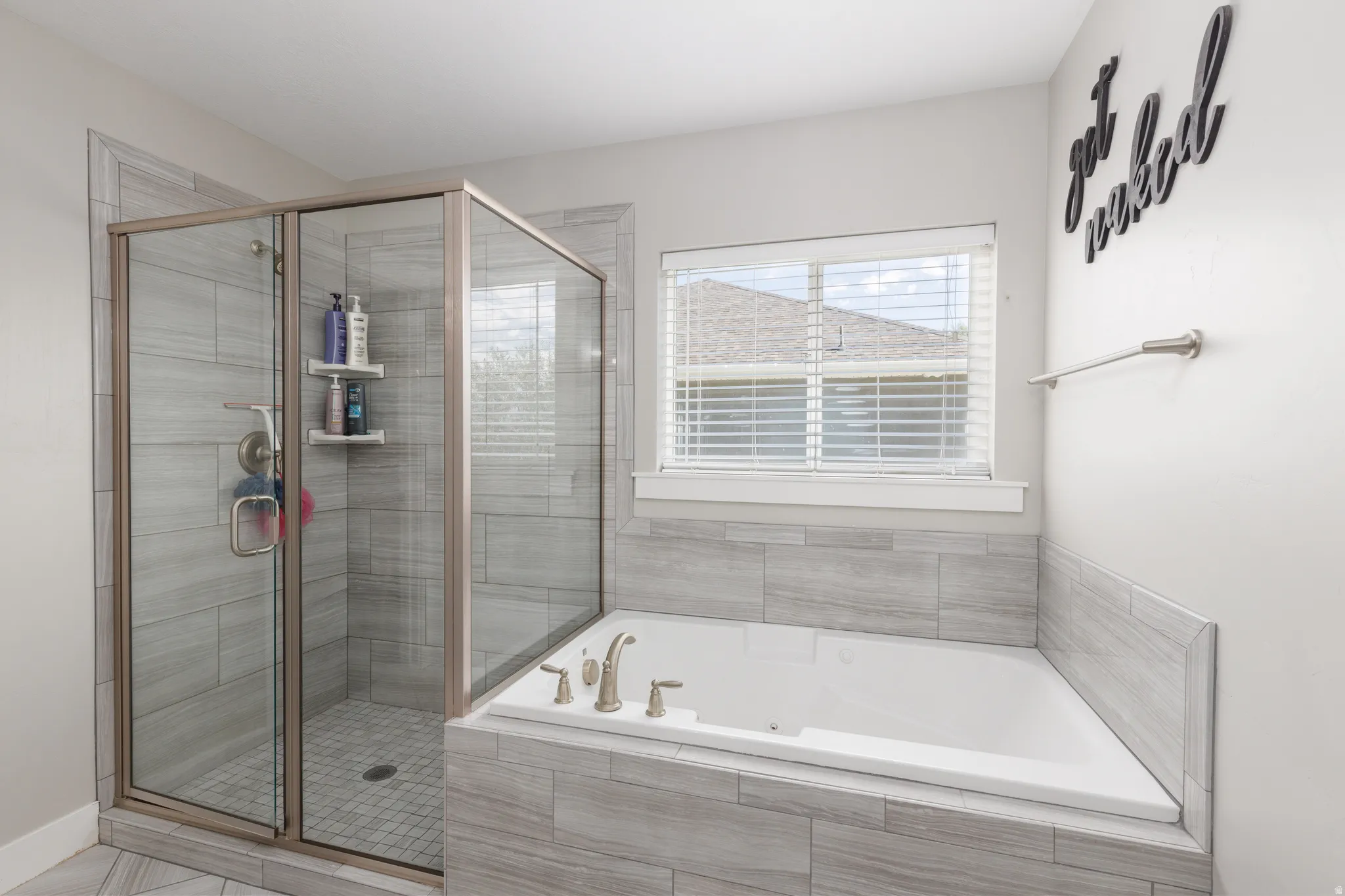 Glass-enclosed shower with tile surround, built-in soaking tub, and tile-wrapped tub deck